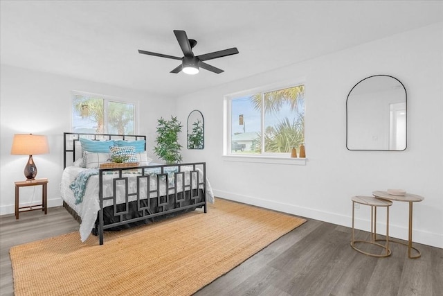 bedroom featuring dark wood-type flooring, ceiling fan, and multiple windows