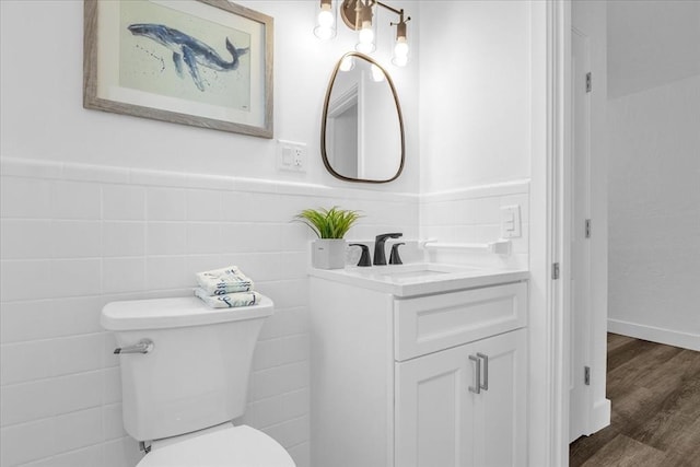 bathroom featuring vanity, wood-type flooring, tile walls, and toilet