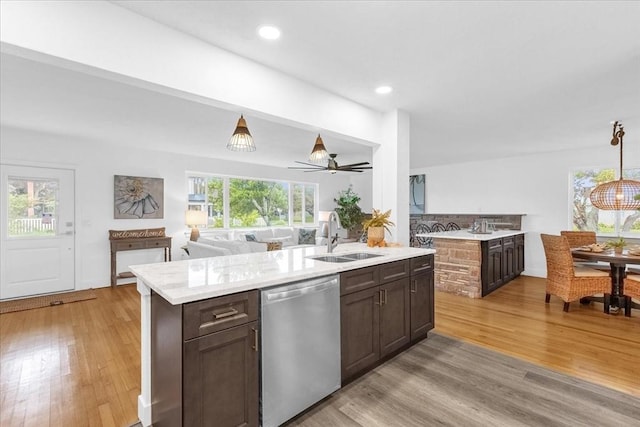 kitchen featuring dishwasher, sink, a kitchen island with sink, and dark brown cabinetry