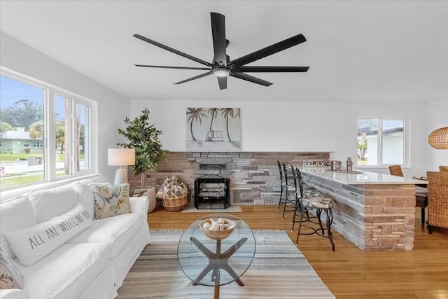 living room featuring a fireplace, light hardwood / wood-style floors, and ceiling fan