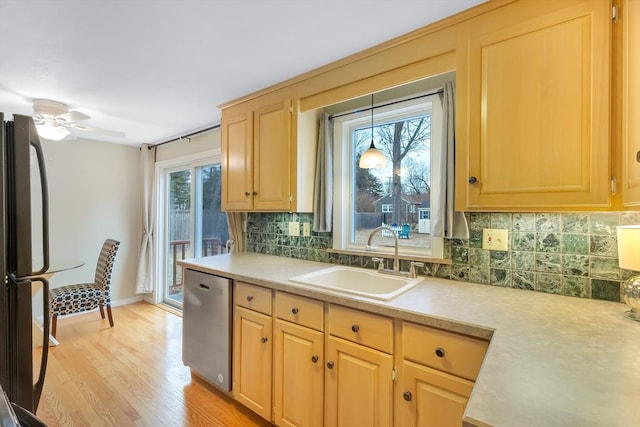 kitchen featuring ceiling fan, stainless steel dishwasher, sink, plenty of natural light, and black refrigerator