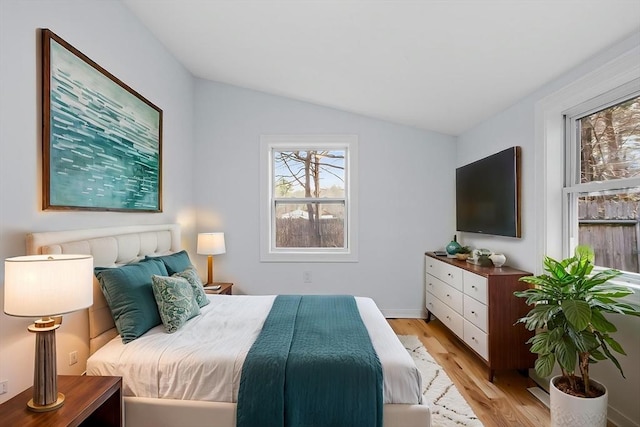 bedroom with baseboards, light wood finished floors, and lofted ceiling