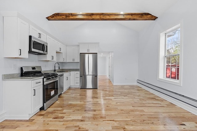 kitchen with lofted ceiling with beams, a baseboard heating unit, a sink, light wood finished floors, and appliances with stainless steel finishes