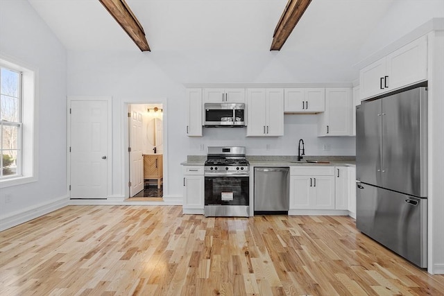 kitchen with lofted ceiling with beams, white cabinets, a sink, light wood-style flooring, and stainless steel appliances