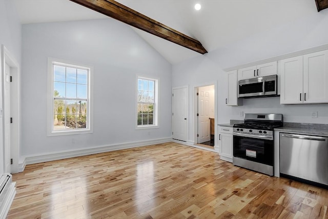 kitchen with appliances with stainless steel finishes, light wood-type flooring, beam ceiling, and white cabinetry