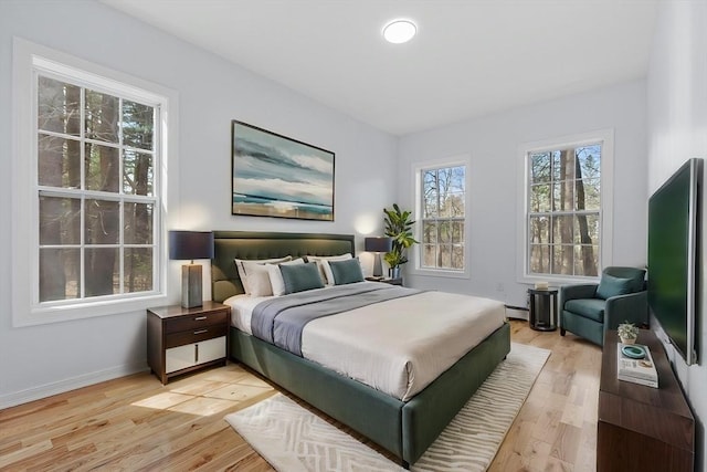 bedroom with baseboards, light wood-style flooring, and a baseboard radiator