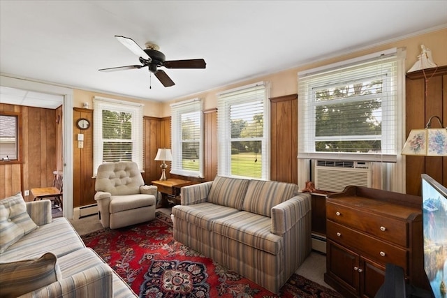 living room with wooden walls, a baseboard radiator, ceiling fan, and plenty of natural light