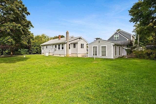back of property with a chimney and a lawn