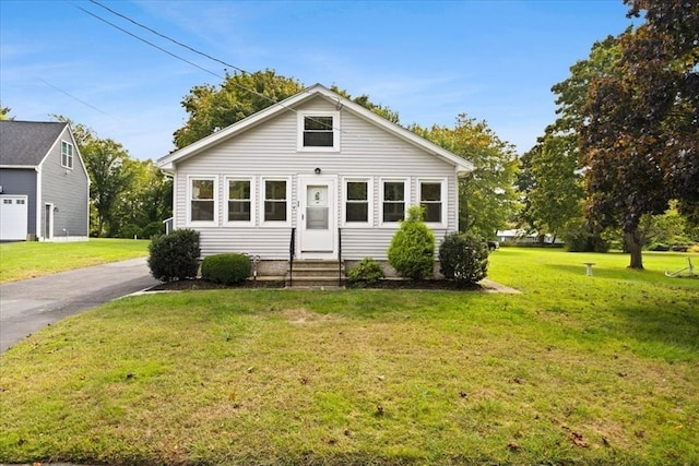 bungalow featuring a garage and a front lawn