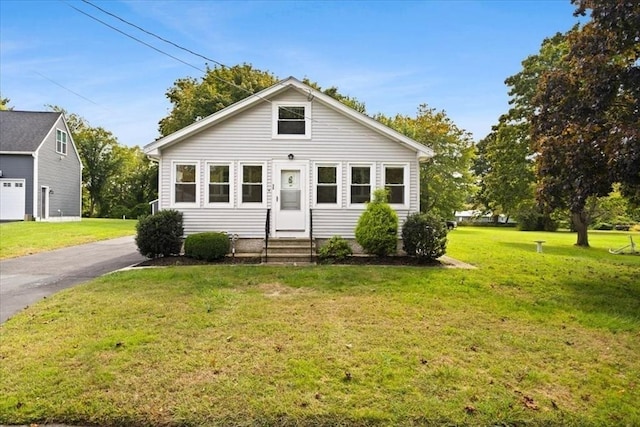 bungalow-style home with a front yard and entry steps