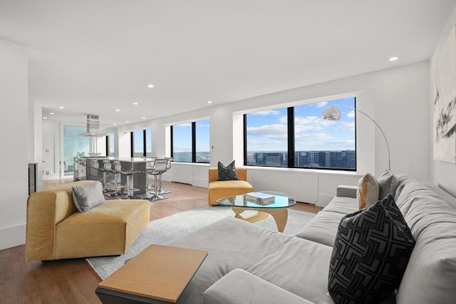 living room featuring light wood-type flooring, a city view, and recessed lighting