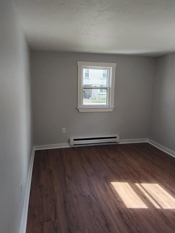 spare room with a baseboard radiator, wood finished floors, and baseboards