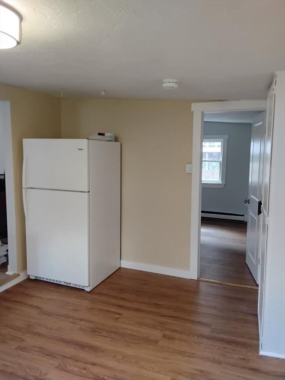 kitchen with light wood finished floors, a baseboard heating unit, freestanding refrigerator, and baseboards