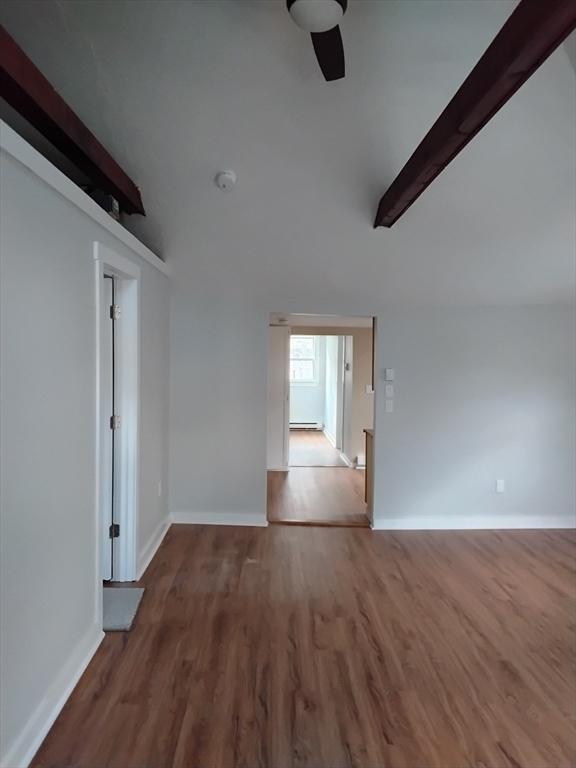 empty room with wood finished floors, lofted ceiling with beams, and a ceiling fan