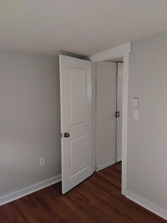 empty room with baseboards and dark wood-style floors