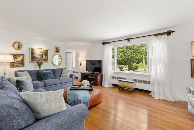 39 Manton Rd, Swampscott, MA 01907 - living area featuring radiator, arched walkways, and light wood finished floors