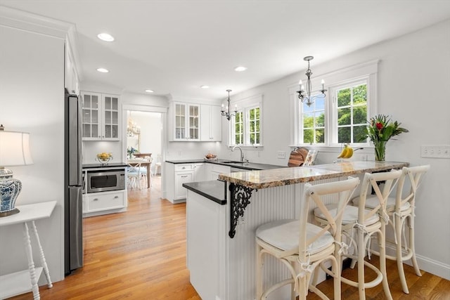39 Manton Rd, Swampscott, MA 01907 - kitchen with stainless steel appliances, a chandelier, a peninsula, a kitchen bar, and white cabinetry
