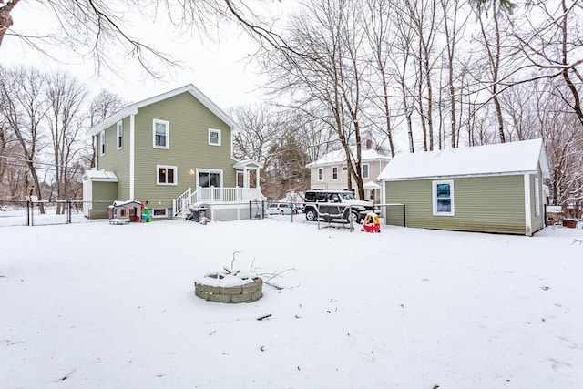 snow covered rear of property featuring an outbuilding and an outdoor fire pit