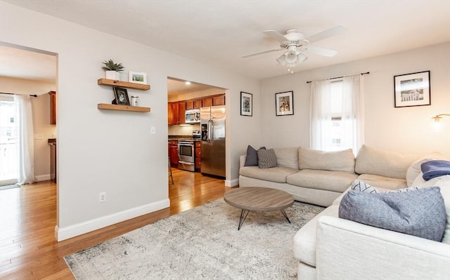 living room featuring ceiling fan, plenty of natural light, and light hardwood / wood-style floors