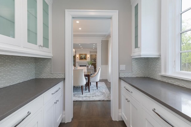 8 Hidden Rd, Weston, MA 02493 - kitchen with dark countertops, white cabinetry, ornamental molding, tasteful backsplash, and glass insert cabinets