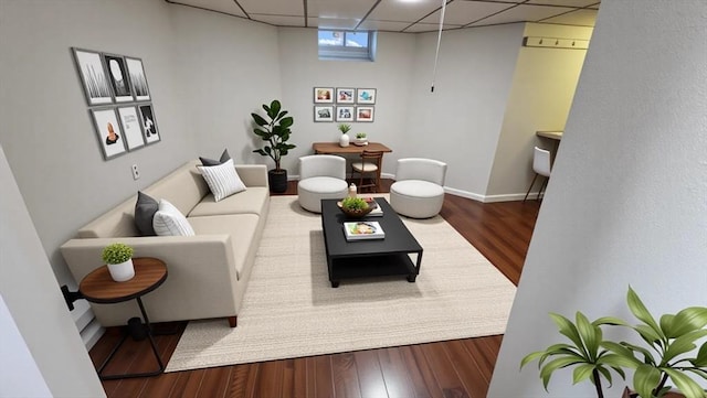 living area featuring baseboards, a drop ceiling, and wood finished floors