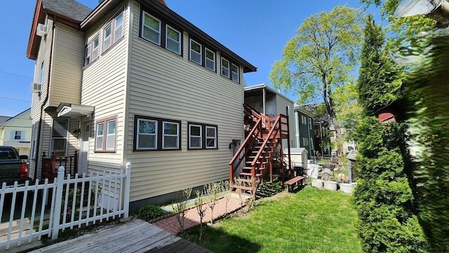 rear view of house with a lawn, stairs, and fence