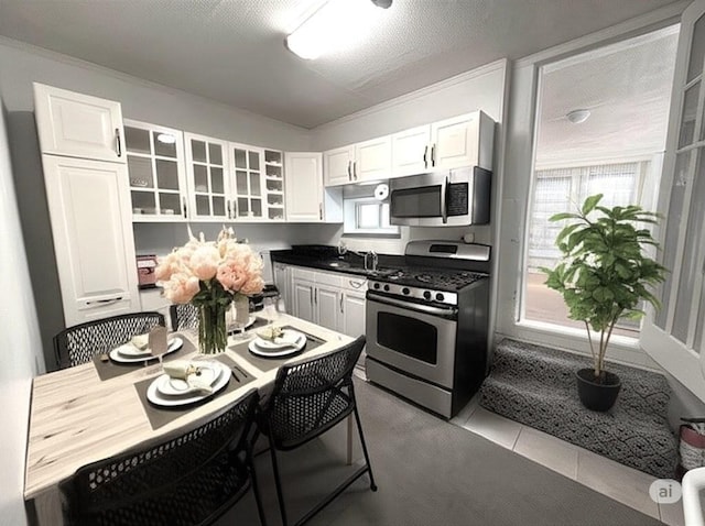 kitchen featuring white cabinetry, tile patterned floors, glass insert cabinets, and appliances with stainless steel finishes