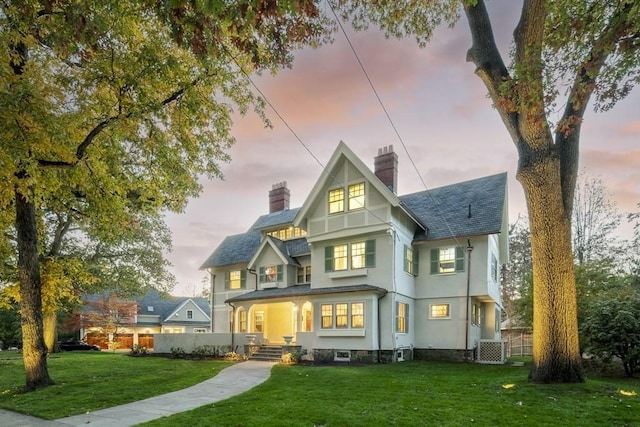 back house at dusk with a yard and central AC unit