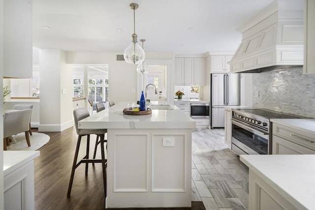 kitchen with premium range hood, a center island with sink, sink, dark hardwood / wood-style flooring, and stainless steel appliances