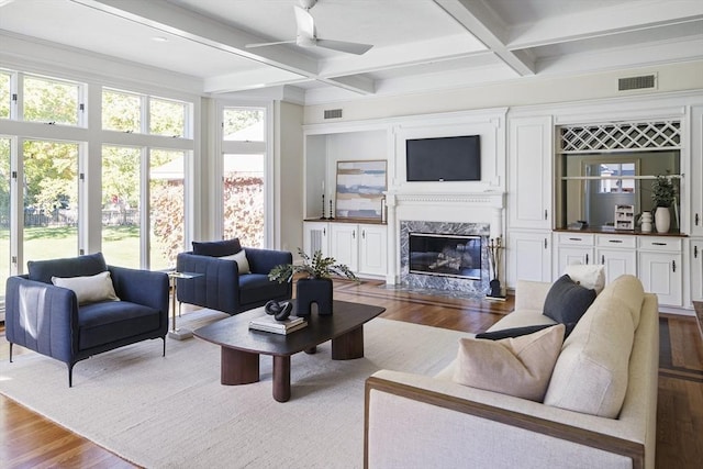 living room featuring a high end fireplace, coffered ceiling, ceiling fan, beam ceiling, and hardwood / wood-style flooring