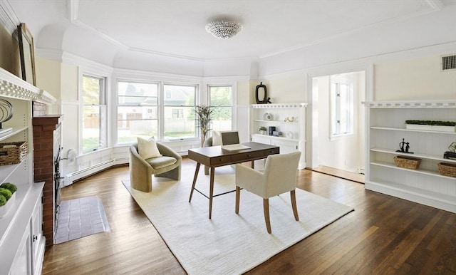 dining space featuring dark wood-type flooring, a baseboard heating unit, and a brick fireplace