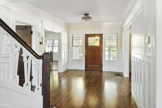 entrance foyer with crown molding, dark wood-type flooring, and a notable chandelier