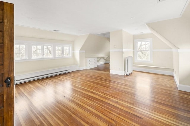 additional living space featuring wood-type flooring, lofted ceiling, baseboard heating, and radiator