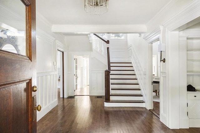 stairs featuring hardwood / wood-style flooring, crown molding, and a chandelier