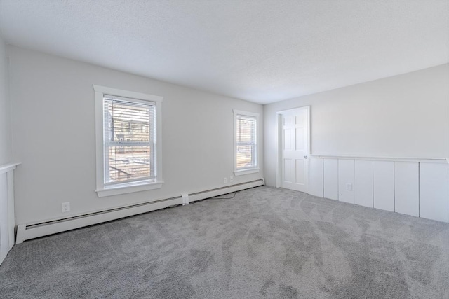 carpeted empty room featuring a baseboard heating unit