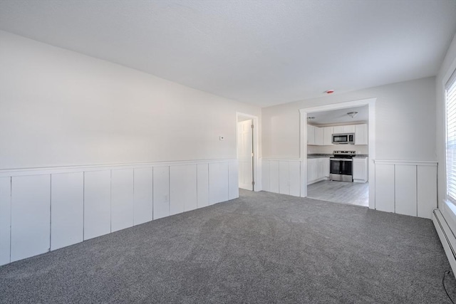 unfurnished living room featuring a baseboard heating unit and light colored carpet