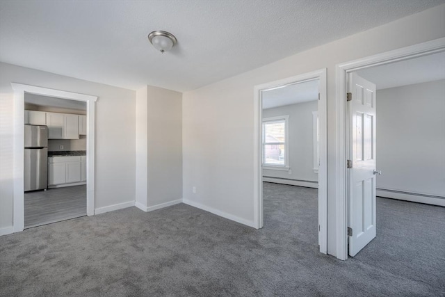 carpeted empty room featuring a baseboard heating unit