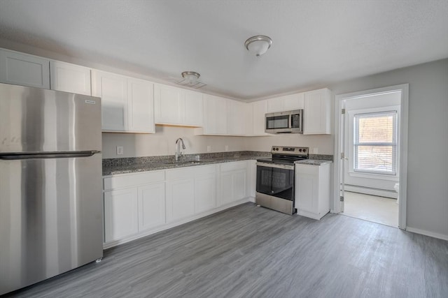 kitchen with a baseboard radiator, sink, white cabinets, stainless steel appliances, and light wood-type flooring