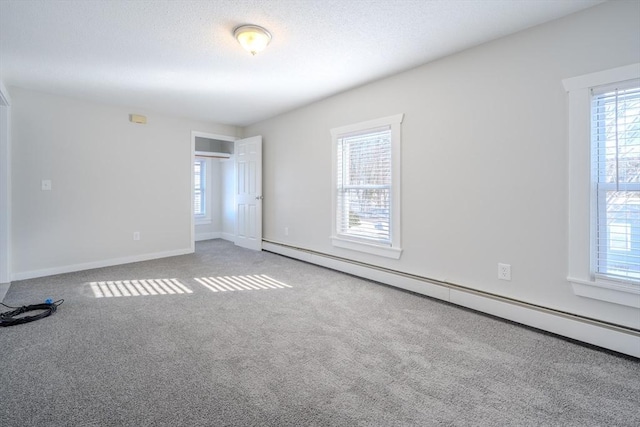 carpeted empty room featuring a baseboard radiator and a textured ceiling