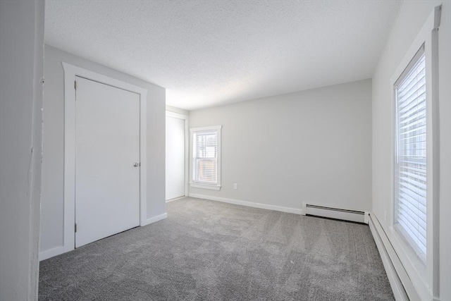 unfurnished room with carpet floors, a textured ceiling, and baseboard heating