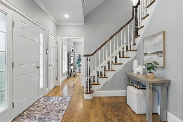 foyer entrance featuring stairway, baseboards, ornamental molding, and wood finished floors