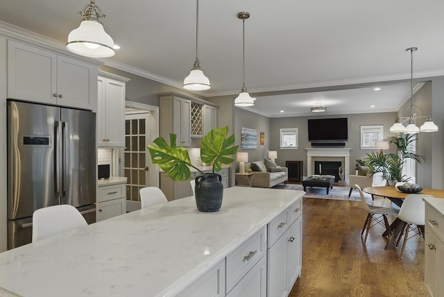 kitchen with dark wood-style flooring, decorative light fixtures, crown molding, a fireplace, and freestanding refrigerator