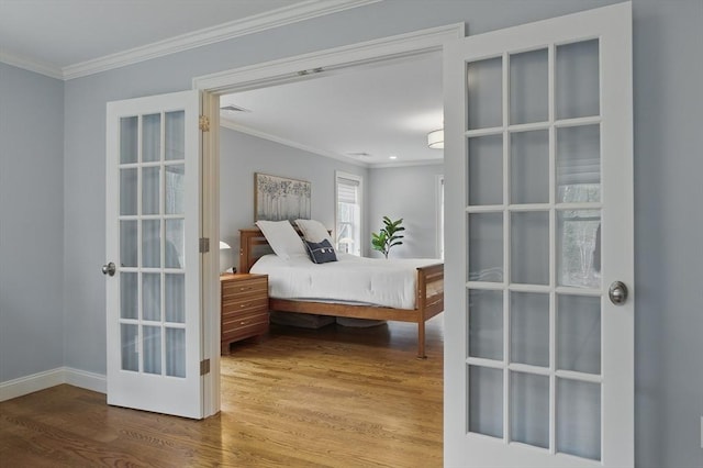 bedroom with french doors, baseboards, wood finished floors, visible vents, and ornamental molding