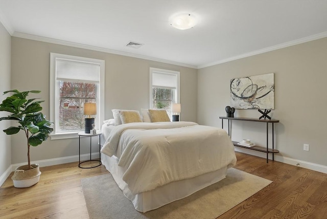 bedroom with crown molding, baseboards, visible vents, and wood finished floors