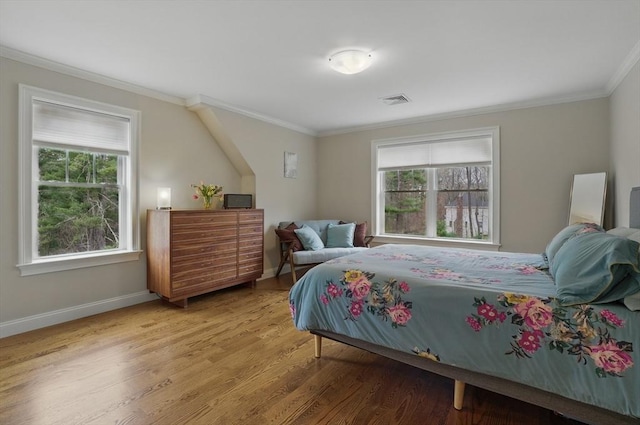 bedroom featuring visible vents, ornamental molding, wood finished floors, and multiple windows