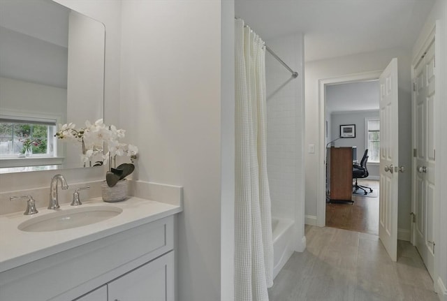 bathroom with a healthy amount of sunlight, vanity, wood finished floors, and shower / tub combo with curtain