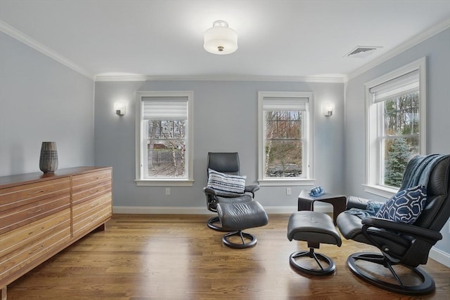 living area featuring baseboards, visible vents, ornamental molding, and wood finished floors