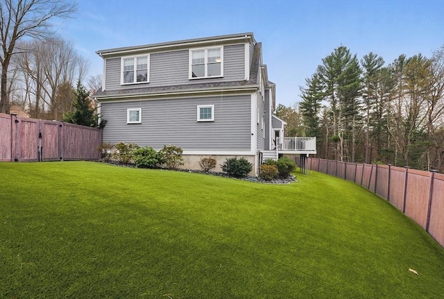 rear view of house with a fenced backyard, a wooden deck, and a yard