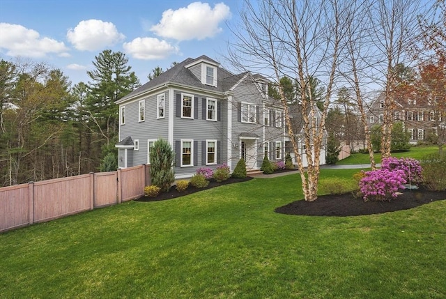 colonial inspired home featuring fence and a front lawn