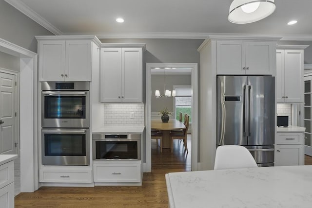 kitchen featuring an inviting chandelier, ornamental molding, decorative backsplash, and appliances with stainless steel finishes